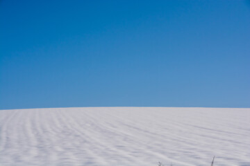 青空と雪が積もった冬の畑
