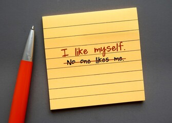 Yellow note paper on gray background with handwritten text NO ONE LIKES ME changed to I LIKE MYSELF...