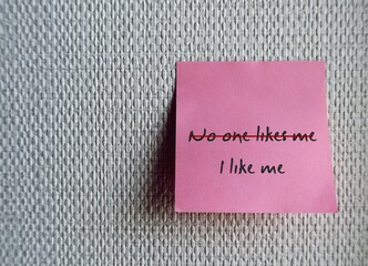 Pink note stick on white wallpaper, written NO ONE LIKES ME  (with red cross out) , I LIKE ME -...