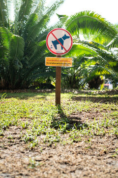 Prohibited to let an animal pets defecating shit in the garden area at public park (English and Thai text language). Sign and symbol for animal object photo, close-up.