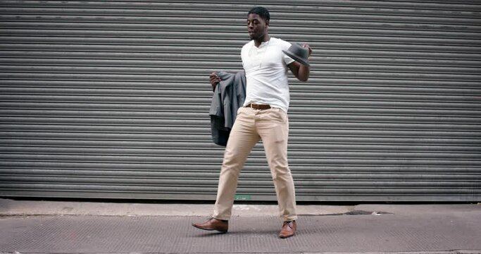 Dance, music and freedom with a black man in the city, dancing against a steel gate outdoor on the street. Art, energy and fashion with a male dancer having fun or moving creative in an urban town