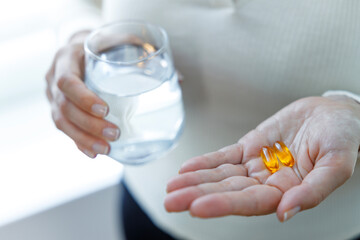 Close up of woman holding vitamin capsules and glass of water. Nutritional Supplements. Capsules vitamin and dietary supplements..
