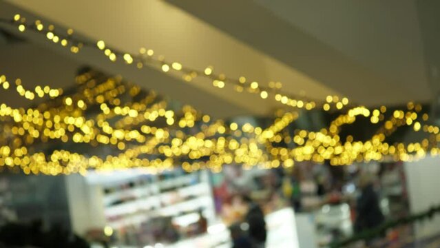 Christmas lights in the Bluer shopping center. New Year's garlands in the Blur shopping center. Retail counters in a busy mall. Christmas mood shining lights.