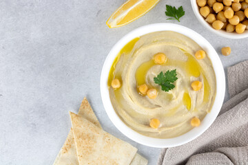 Plate of classic hummus with parsley, olive oil and pita on a gray background, top view. copy space. Arabic, Middle Eastern, Turkish cuisine.