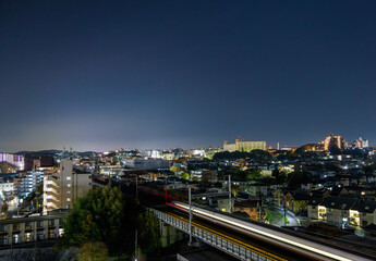 Fototapeta na wymiar Train moves through quiet cityscape at night