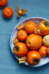 Oranges, tangerines and persimmons on a plate