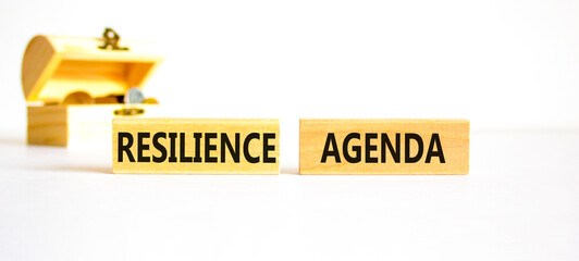 Resilience agenda symbol. Concept word Resilience agenda typed on wooden blocks. Beautiful white table white background. Wooden chest with coins. Business and resilience agenda concept. Copy space.