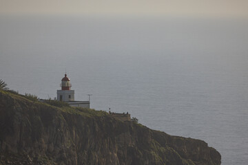 Fototapeta na wymiar Amazing lighthouse on a high cliff on the Madeira coast in Portugal.