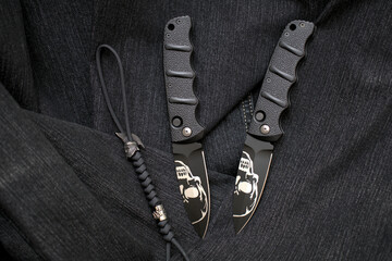 Folding knives cutting black stainless steel blade and handle wicker lanyard helmet bead denim background