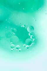 Abstract background in green cold tones. Distortion in water with oil drops.