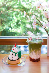 Snowman chocolate tart and cold strawberry green tea on wooden table in Japanese cafe, homemade bakery..Holiday dessert for Christmas and New Year season..Homemade Christmas cake decorated  snowman.