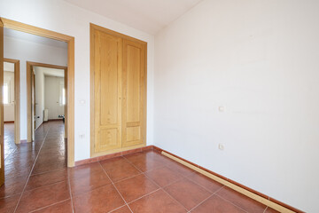 bedroom with a two-section built-in wardrobe with oak doors and reddish-brown stoneware floors and access to a distributor