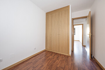 bedroom with a two-section built-in wardrobe with large oak sliding doors and wooden floors, a single-pane aluminum window with views, access doors of the same material and an aluminum radiator below
