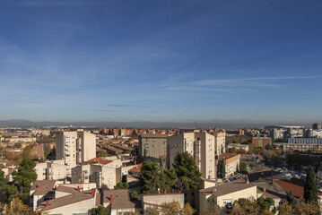 Fototapeta premium Views of building facades and roofs of the city on a sunny winter day with the mountains in the background