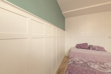Bedroom with wooden frieze on the walls, bed with fuchsia bedspread and wooden floors