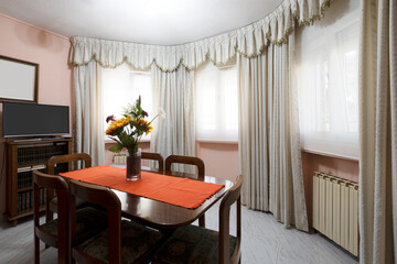 Separate dining room in a semicircular room with radiators and wooden dining tables with matching chairs
