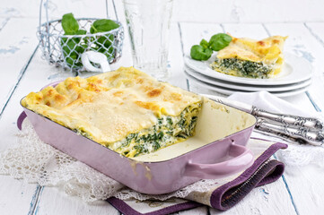 Traditional Italian pasta lasagne alla spinaci with spinach and bechamel sauce served as close-up in a design casserole - obrazy, fototapety, plakaty