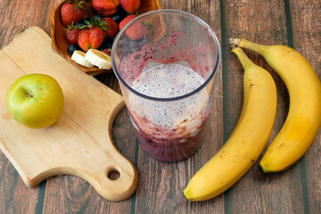 Making Fruit Smoothie with banana, blueberry, apple, strawberry and milk. Blender filled with fresh whole fruits for making a smoothie