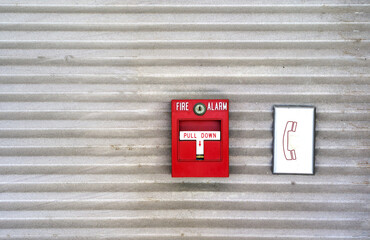 The red fire alarm is attached to the wall and the cement wall of the factory to be used as a...