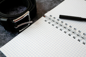empty notebook and dark leather male belt as ptsd symbol on black background, ptsd concept. Post...