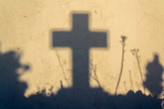 Shadow of a cross on a grave in a Greek cemetery at dawn