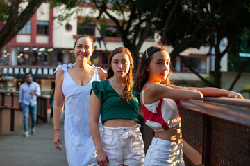 Tourists at one of the bridges along the Cali River Boulevard in the city of Cali in Colombia. Mother and teenager daughters traveling concept. Happy family concept.