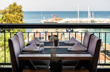 Dinner setting at harborside restaurant with sea harbor and yachts in background: moody and romantic