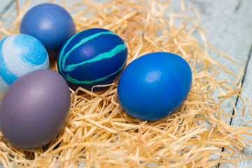 Fototapeta na wymiar Blue decorated easter eggs in straw nest