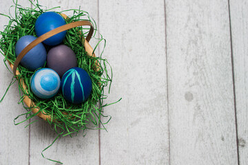 Basket with blue colored Easter Eggs on whitewashed wood