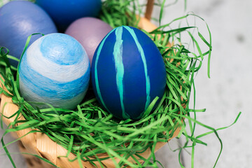 Basket with blue colored Easter Eggs on whitewashed wood