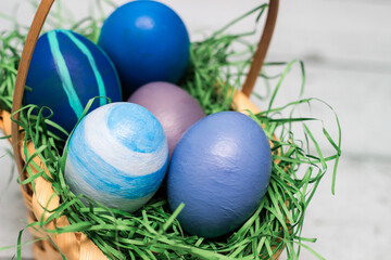 Basket with blue colored Easter Eggs on whitewashed wood