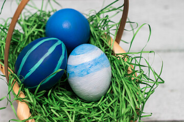 Basket with blue colored Easter Eggs on whitewashed wood