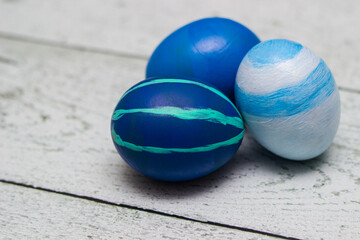 Three blue painted Easter eggs on whitewashed wood