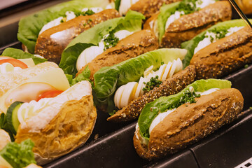 Variety of tasty sandwiches with salad and eggs in the window of a store or supermarket. Snacks and fastfood concept