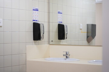 Public Bathroom or restroom washing sink with mirror and hand soap.
