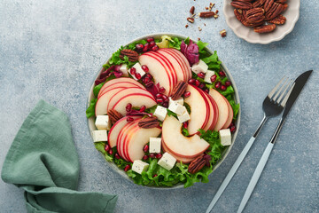 Salad. Fresh fruit green salad with feta cheese, apple, pomegranate, pecan and lettuce on white plate. Idea for healthy delicious winter Christmas salad. Healthy balanced eating. Top view.