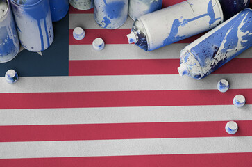 Liberia flag and few used aerosol spray cans for graffiti painting. Street art culture concept,...