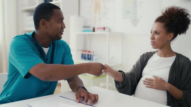 Male gynecologist shaking hands with pregnant patient, prenatal care, healthcare