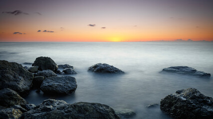 Sunset at Sea, stones on the shore, Amazing perfect pink dreamy looking sunset. Smooth water