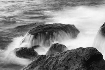 Breaking wave at volcanic pebble beach