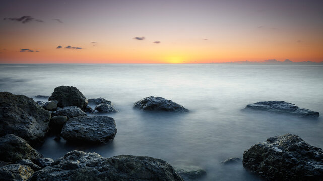 Sunset at Sea, stones on the shore, Amazing perfect pink dreamy looking sunset. Smooth water © Aleksandr Matveev