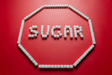 stop sign is made up of sugar cubes on a red background. stop eating sugar concept