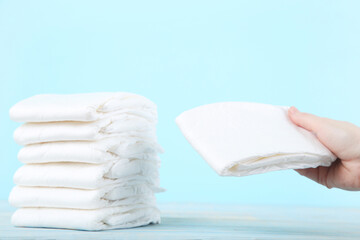 Baby diapers with female hand on blue background