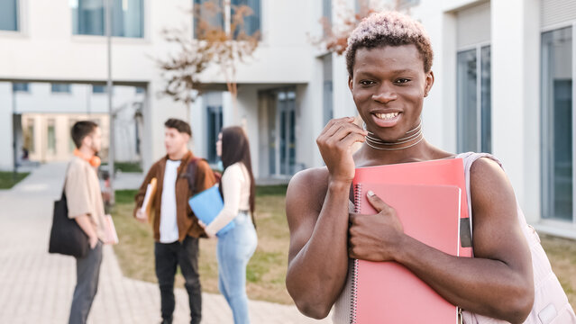 Transgender person smiling at the camera standing in a university campus