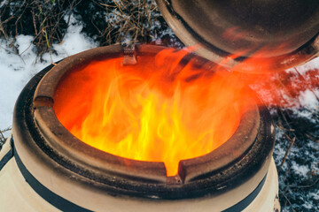 Upper neck of tandoor stove close-up. Flames erupting from traditional clay oven of the peoples of...