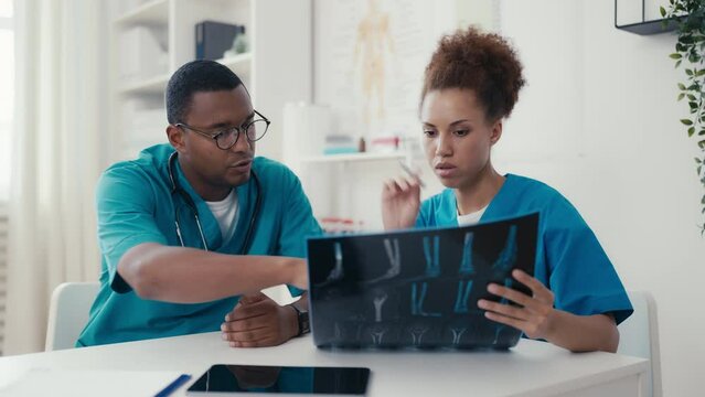 African American doctors examining x-ray image of patient, colleagues teamwork