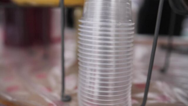 New plastic cup in stack. Close up shot of empty disposable cups standing upside down in pile, small tray at top of vending machine
