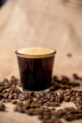 tasse de café avec de la mousse dans un décor de toile de jute et de café en grains