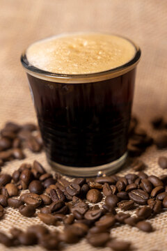 petit café avec sa mousse dans des grains de café torréfié