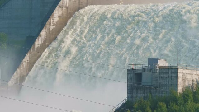 Spillway of hydroelectric power station near city. Hydropower plant throws out surplus water. Ecological industrial disaster, environmental man-made accident. Flooding of a residential area